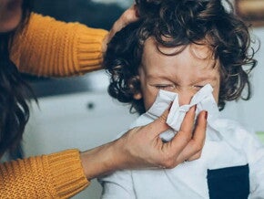 Mama limpiando con pañuelo la nariz de su hijo