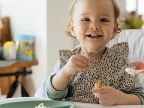 Bebe alegre comiendo con su mama