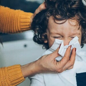 Mama limpiando con pañuelo la nariz de su hijo