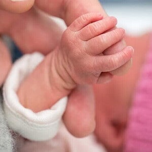 Bebe con bajo peso agarrando el dedo