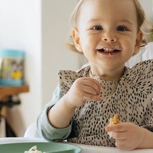 Bebe alegre comiendo con su mama