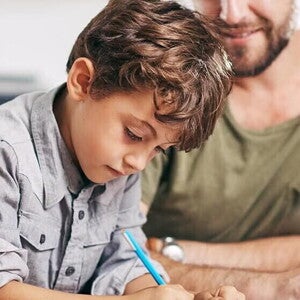 Niño realizando su tarea con su padre