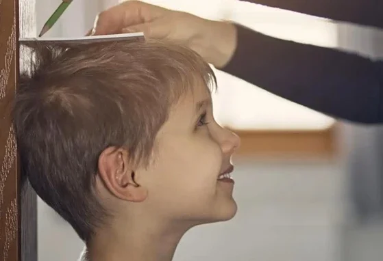 Adulto tomando nota de la altura de un niño
