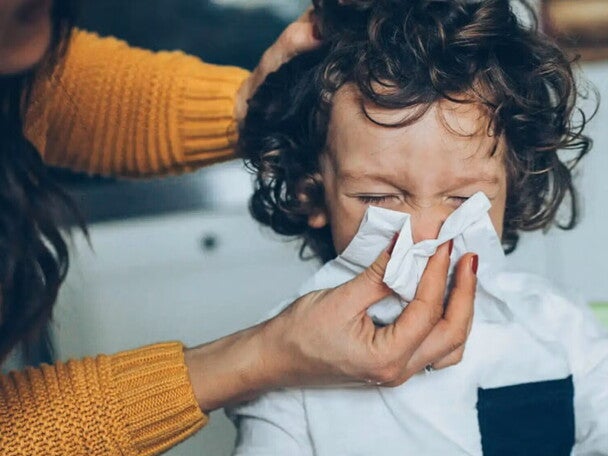 Mama limpiando con pañuelo la nariz de su hijo