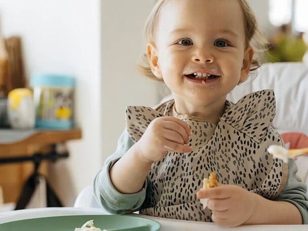 Bebe alegre comiendo con su mama