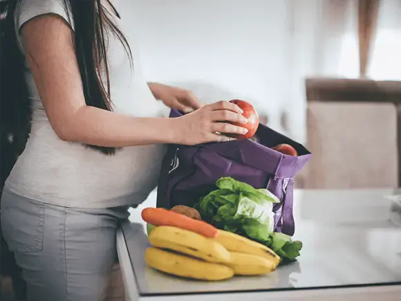 Dieta micro y macronutrimentos para reducir riesgos Embarazada sacando frutas y verduras